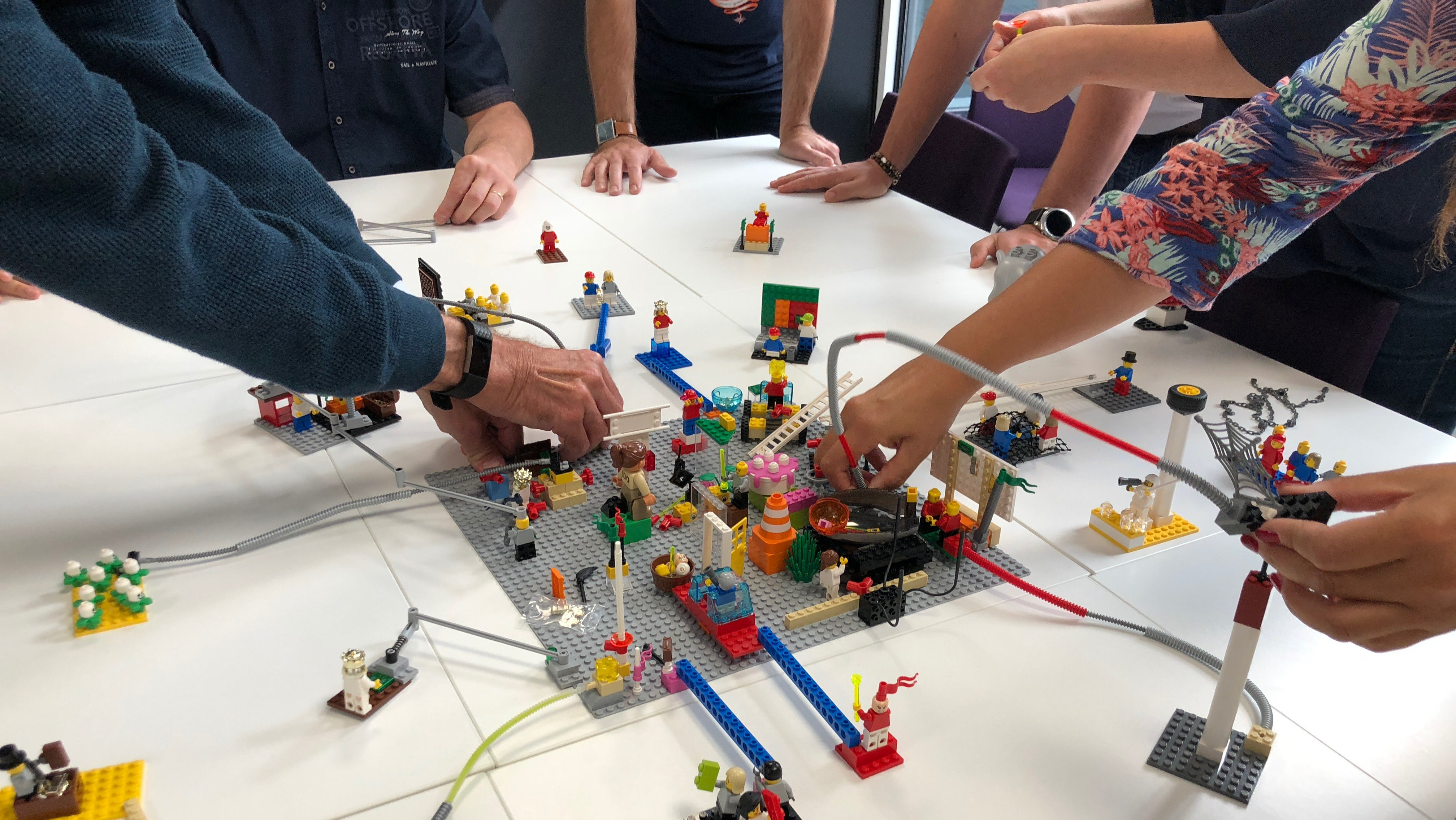 Teilnehmer eines LEGO® SERIOUS PLAY® Workshops bauen Verbindungen auf und spielen Szenarien mit Modellen