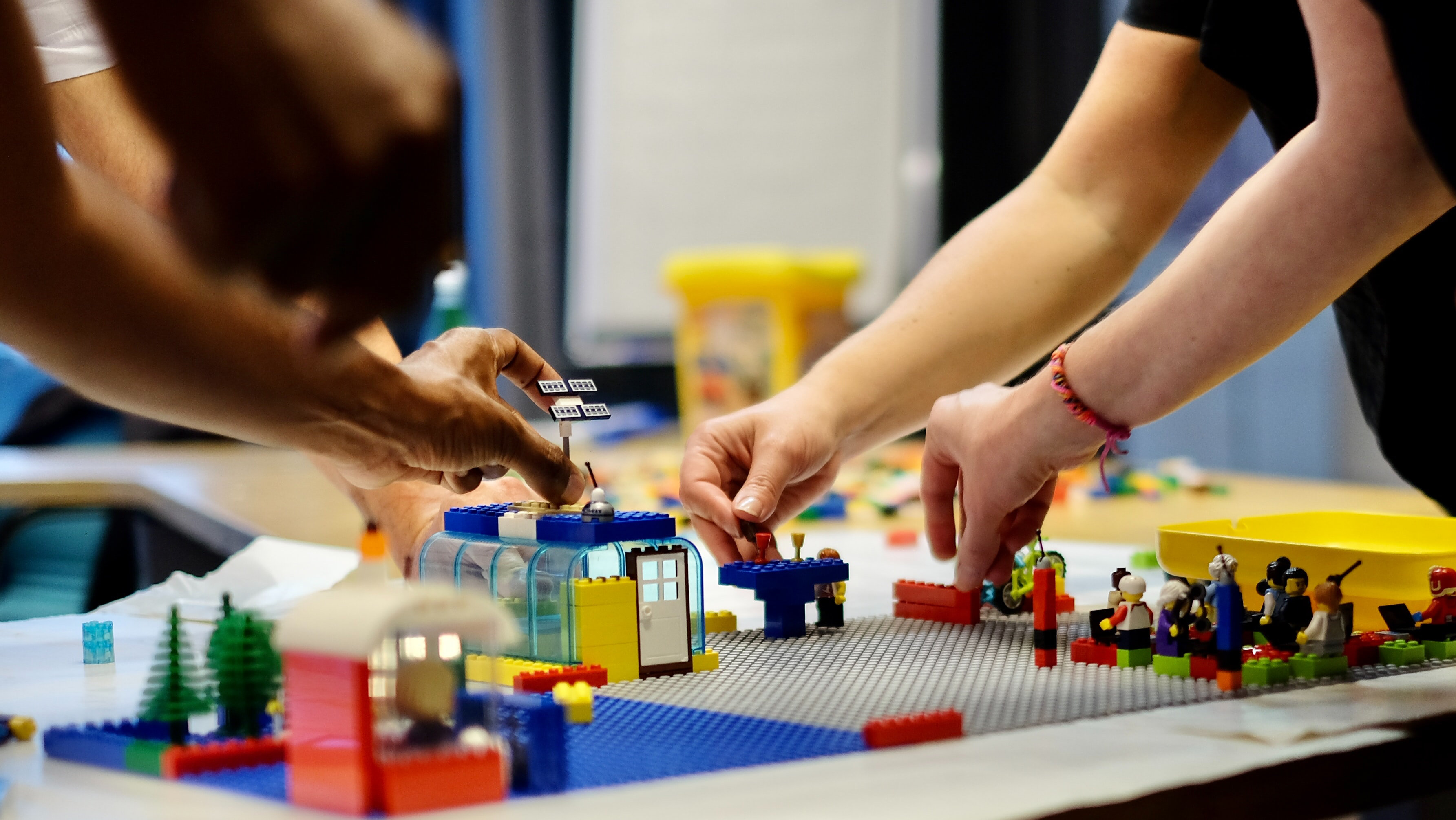 Teilnehmer eines LEGO® SERIOUS PLAY® Workshops beim Bau eines gemeinsamen Modells